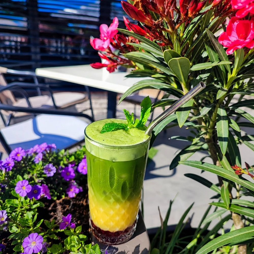 Vrstvený matcha drink s mätou na terase plnej kvetov